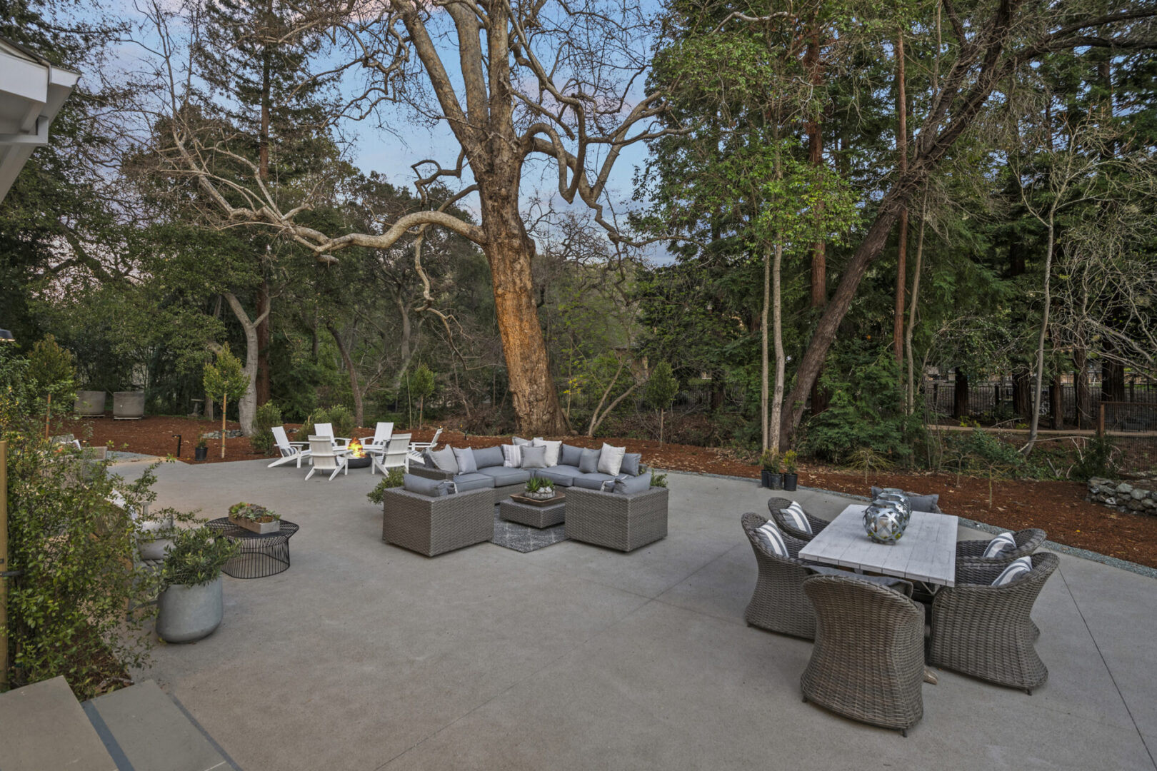 A patio with tables and chairs around an outdoor fire pit.