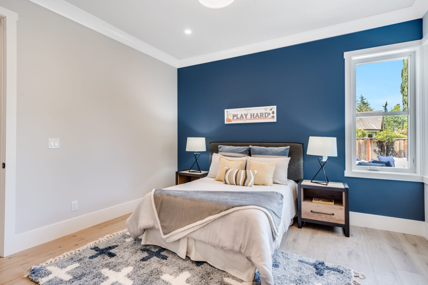 A bedroom with blue walls and white bedding.