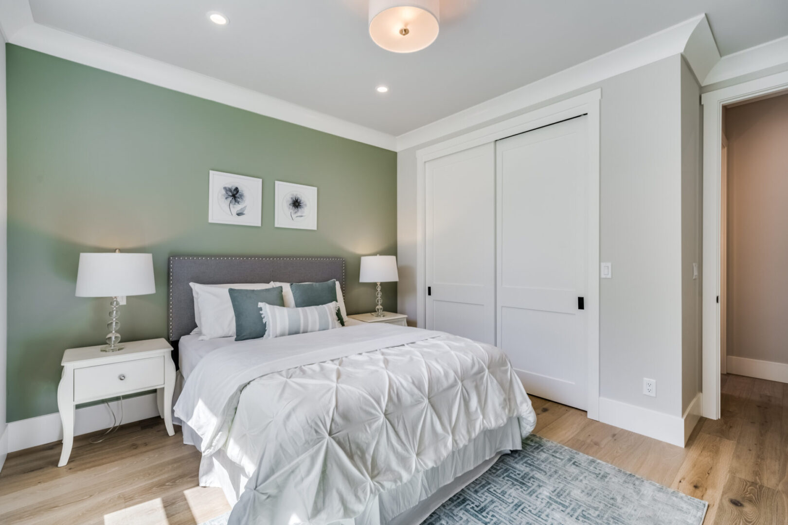 A bedroom with green walls and white bedding.